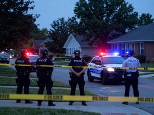 Police investigation scene with caution tape and flashing lights.